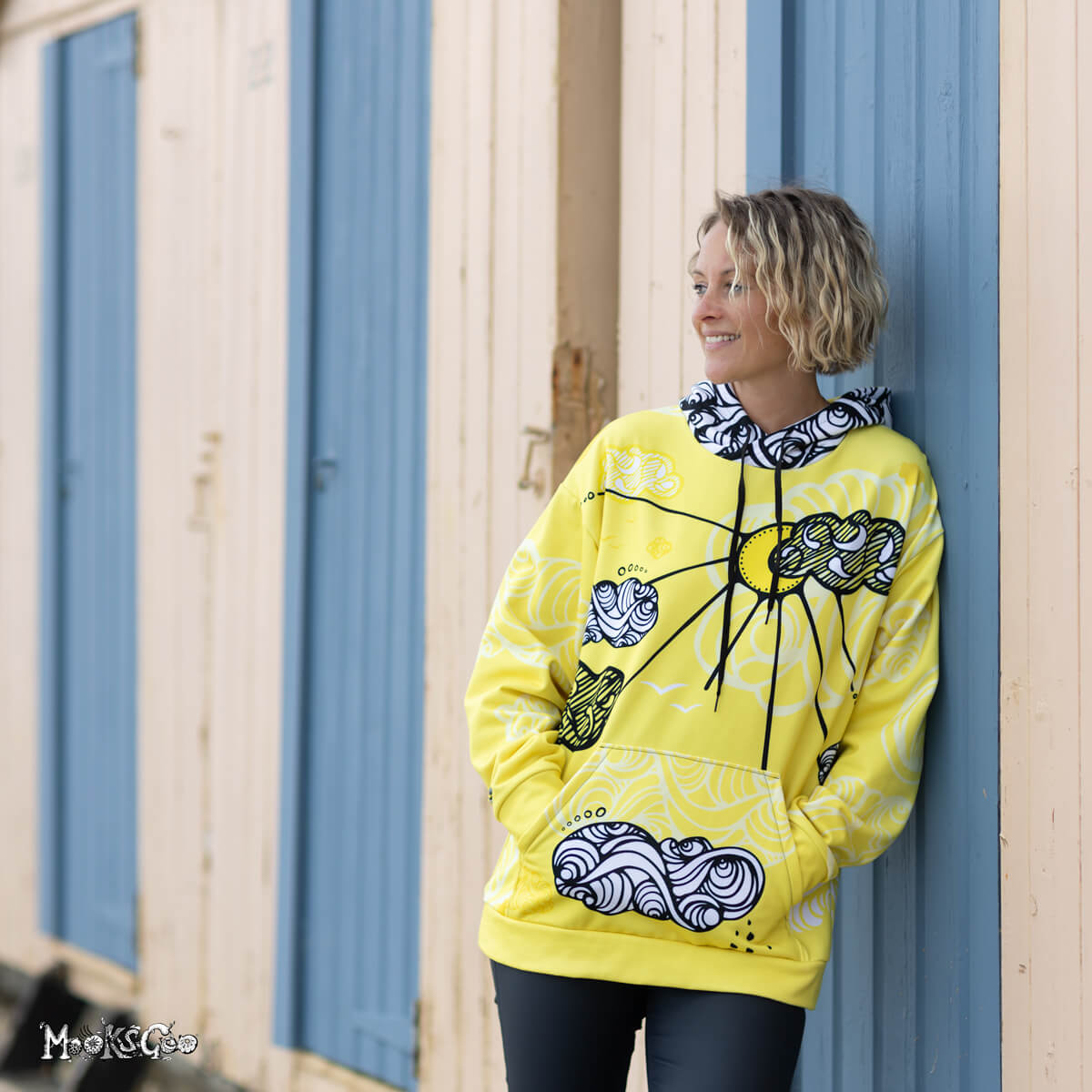 Quirky and bright Sunny Sunshine recycled hoodie, with a yellow, black and white illustrated design by MooksGoo. Model is Michelle Lott (MooksGoo) wearing a size L. Photographed by Julian Winslow along Shanklin Esplanade on the Isle of Wight
