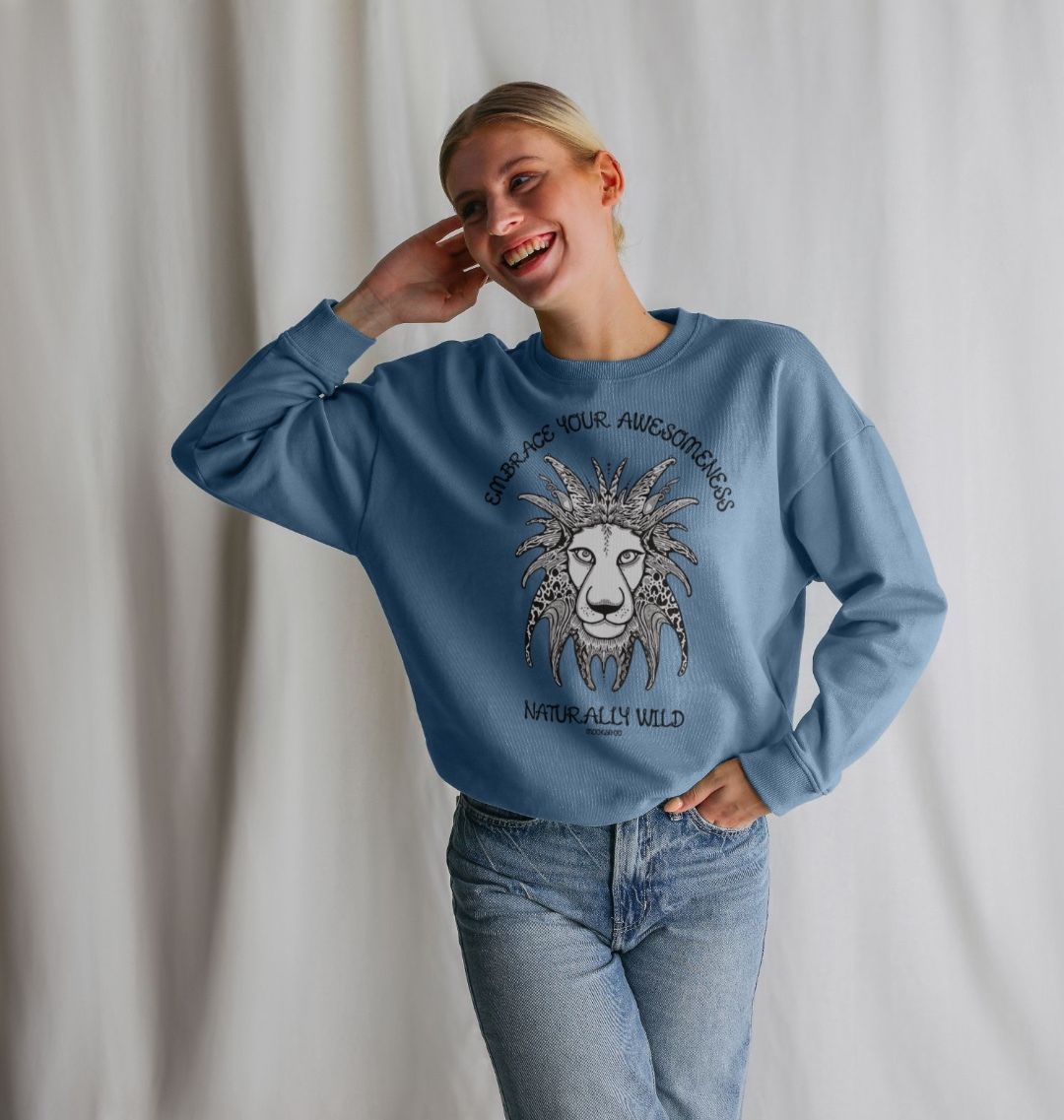 Model with blonde hair wearing an Solent blue organic cotton oversized sweatshirt with embrace your awesomeness naturally wild fun typography, and an illustrated wild lion, designed by MooksGoo
