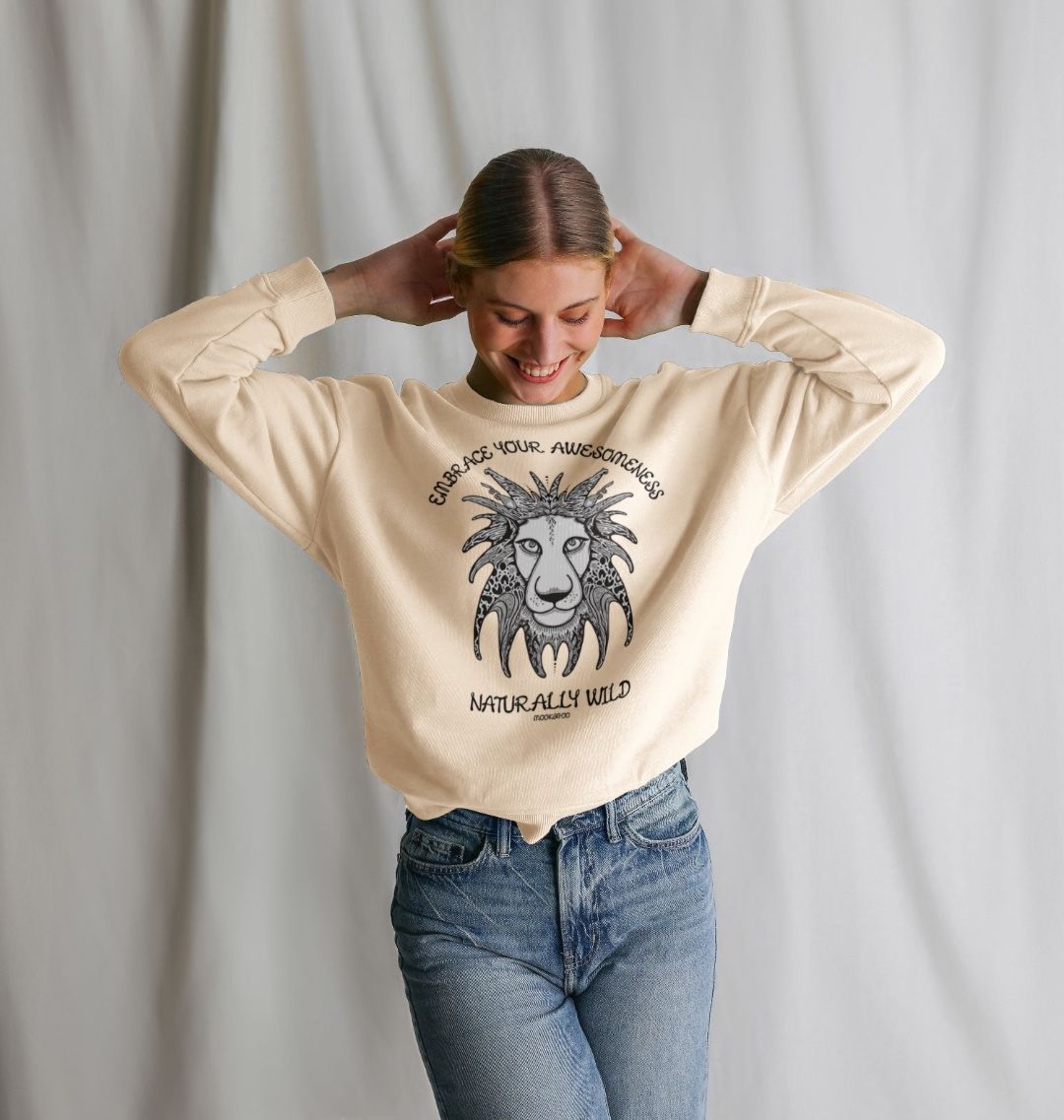 Model with brown hair wearing an oat cream organic cotton oversized sweatshirt with embrace your awesomeness naturally wild fun typography, and an illustrated wild lion, designed by MooksGoo