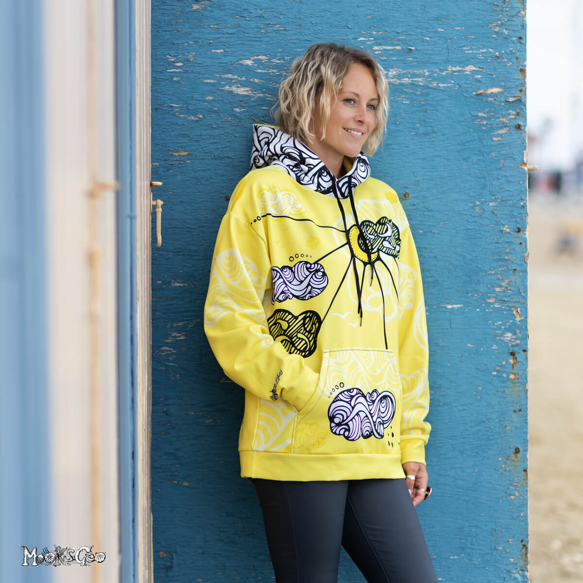 Fun sunshine themed hoodie, with a yellow, black and white design by MooksGoo. Model is Michelle Lott (MooksGoo) wearing a size L, pictured on Shanklin seafront on the Isle of Wight