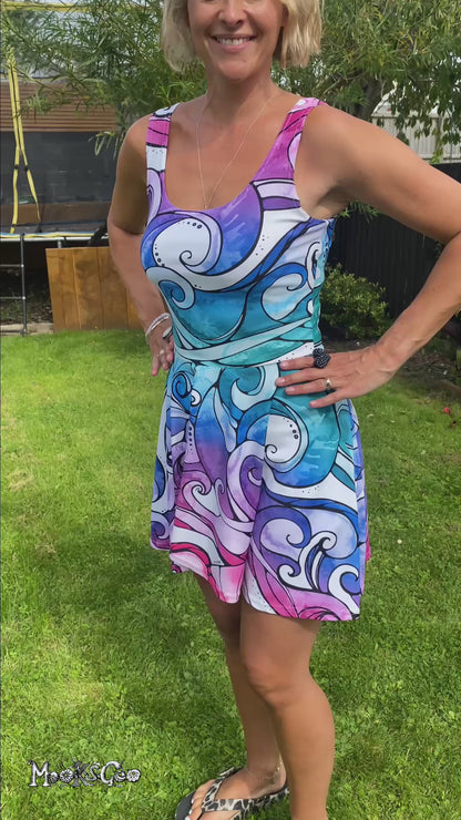 A woman wearing a bright rainbow wave flared dress, showing all angles. Designed by MooksGoo