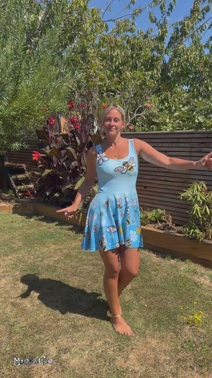 A young woman wearing a bright and bold bees, honey and flower illustrated sleeveless flared dress, designed by MooksGoo