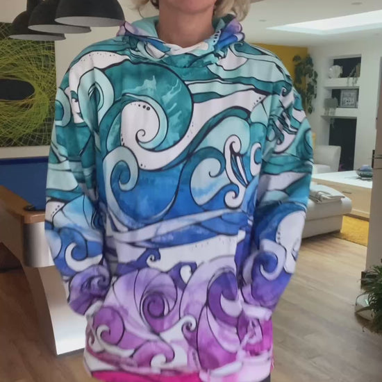 A woman wearing a colourful rainbow hoodie with illustrated waves, walking in a modern sitting room, designed by MooksGoo