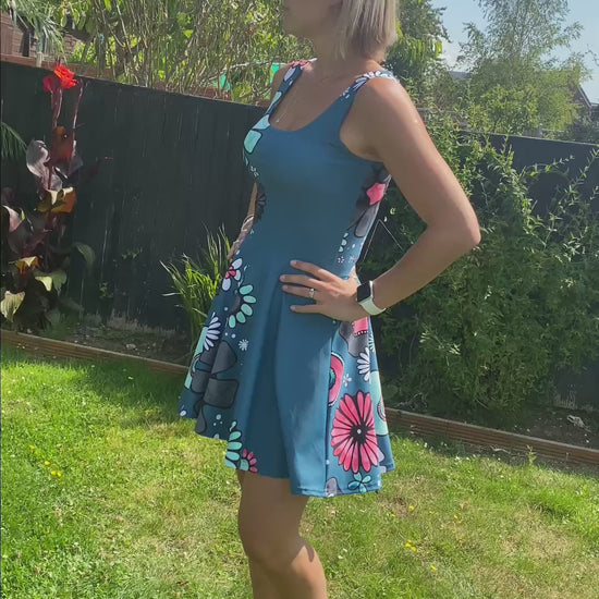 Model wearing a teal floaty dress, with illustrated pink and turquoise flowers, designed by MooksGoo