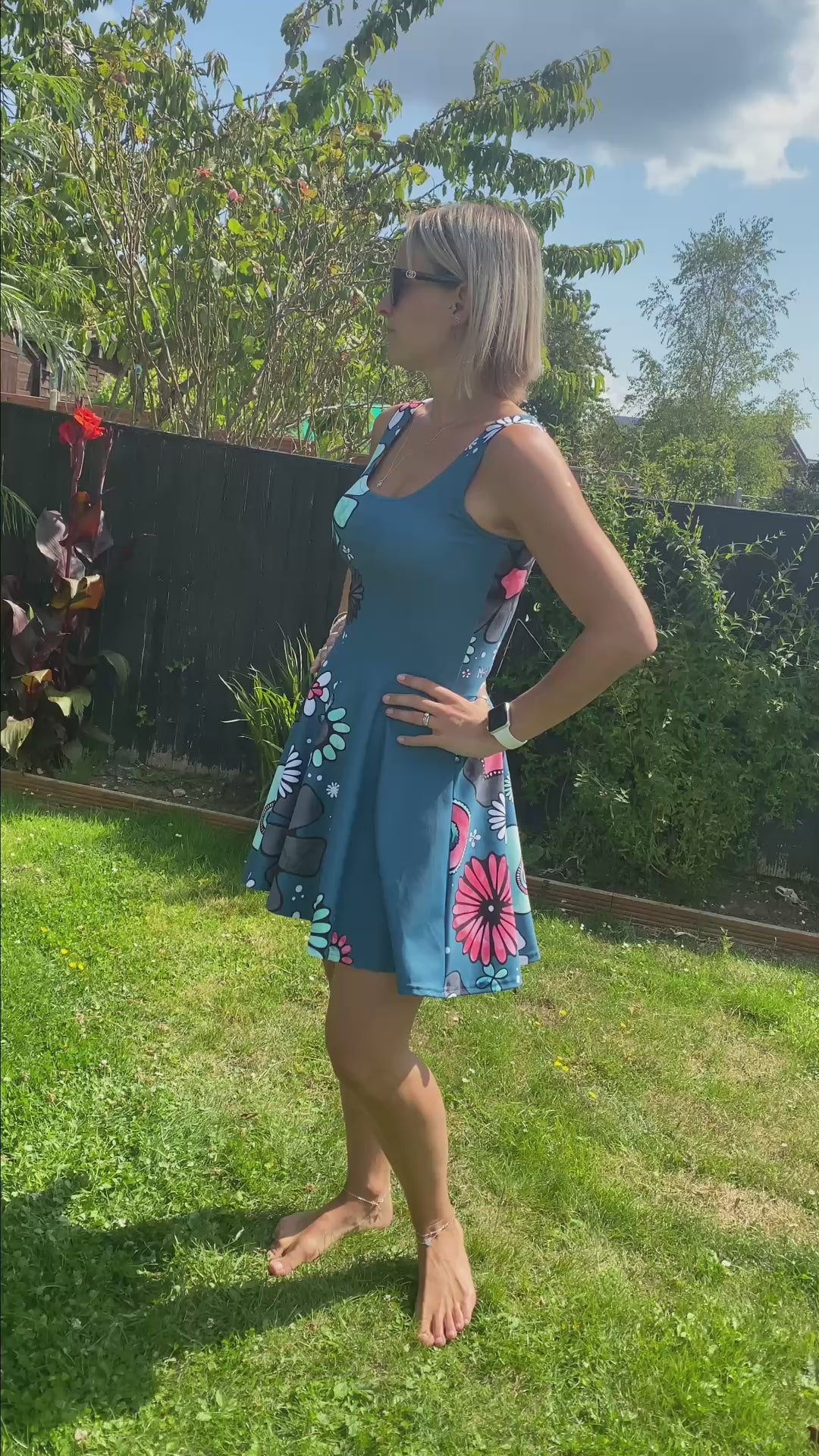 Model wearing a teal floaty dress, with illustrated pink and turquoise flowers, designed by MooksGoo