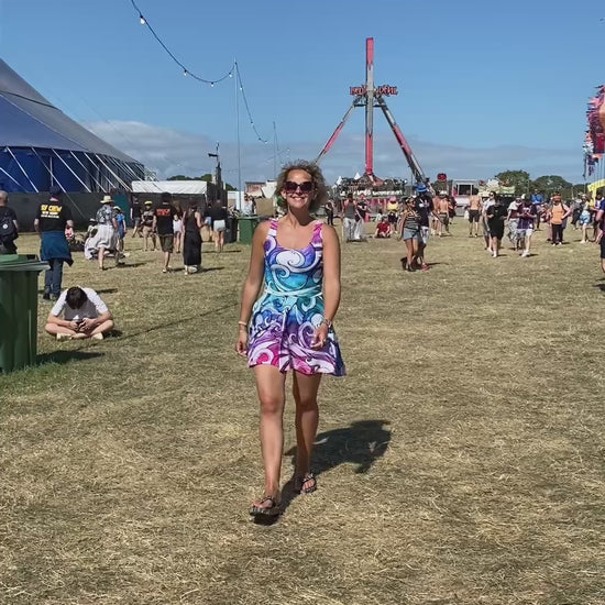 A woman at the Isle of Wight Festival, dancing in a rainbow wave flared dress, designed by MooksGoo