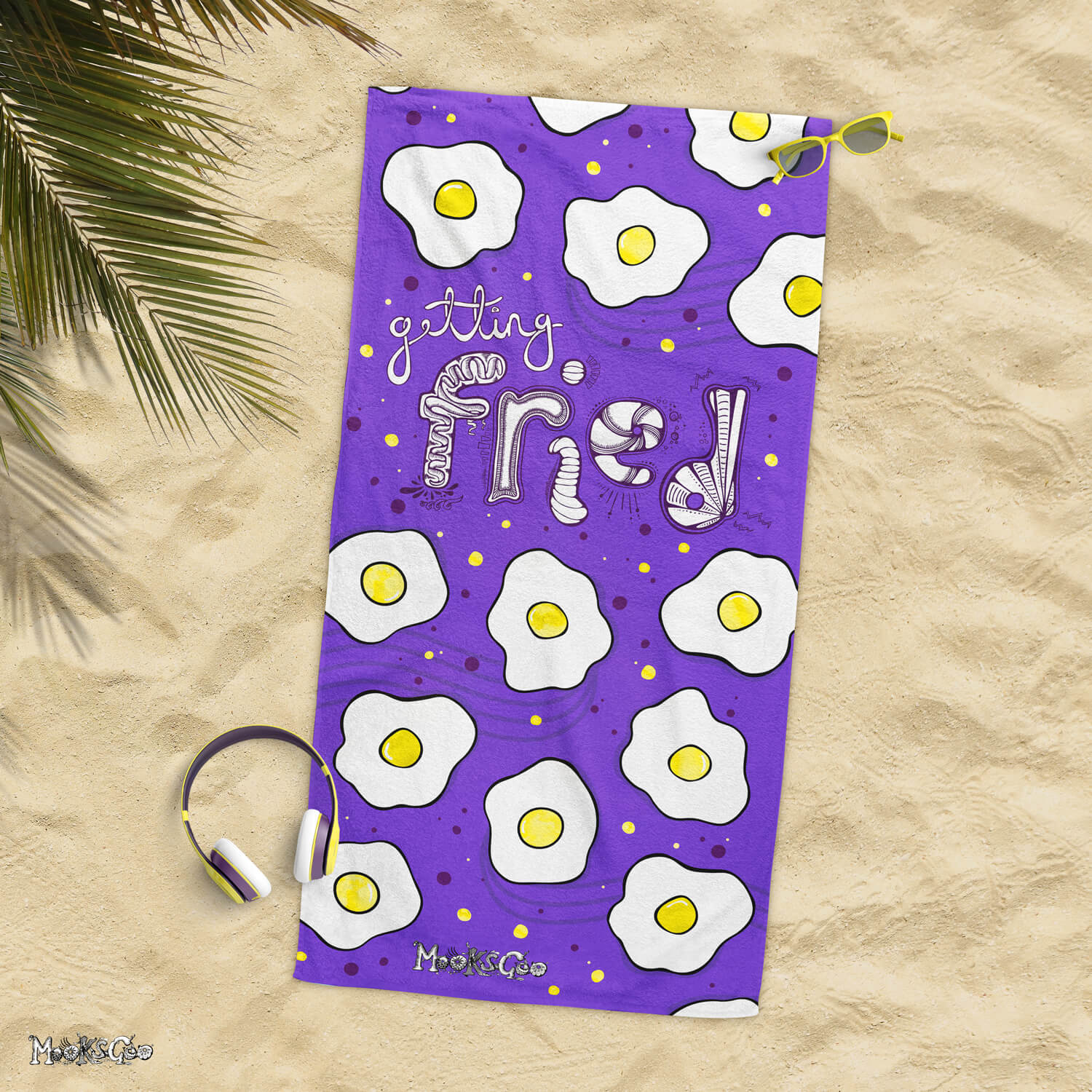 Getting Fried beach or bathroom towel with illustrated fried eggs, laying flat on a sandy beach, designed by MooksGoo