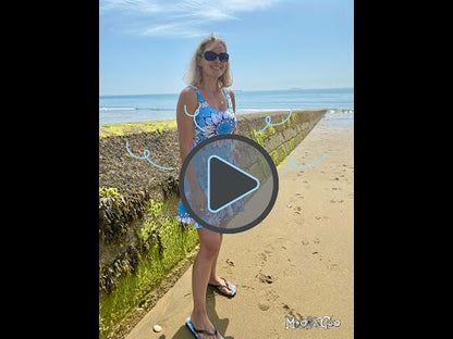 Product video of a sky blue Quirky and fun women's floaty light skater dress with hand drawn illustrated black and white sunflowers, dots and wheels, designed by MooksGoo, filmed on the beach on the Isle of Wight